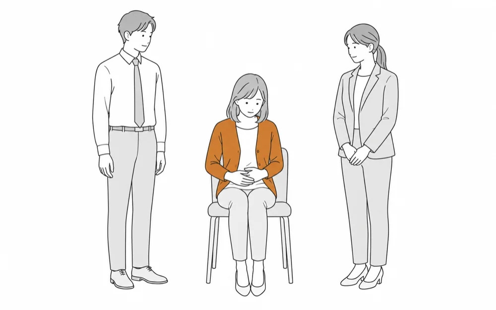 腹部に手を当てて椅子にうつむいて座る女性と、その両側に立って気づかうように見守る同僚の男性と女性のイラスト
