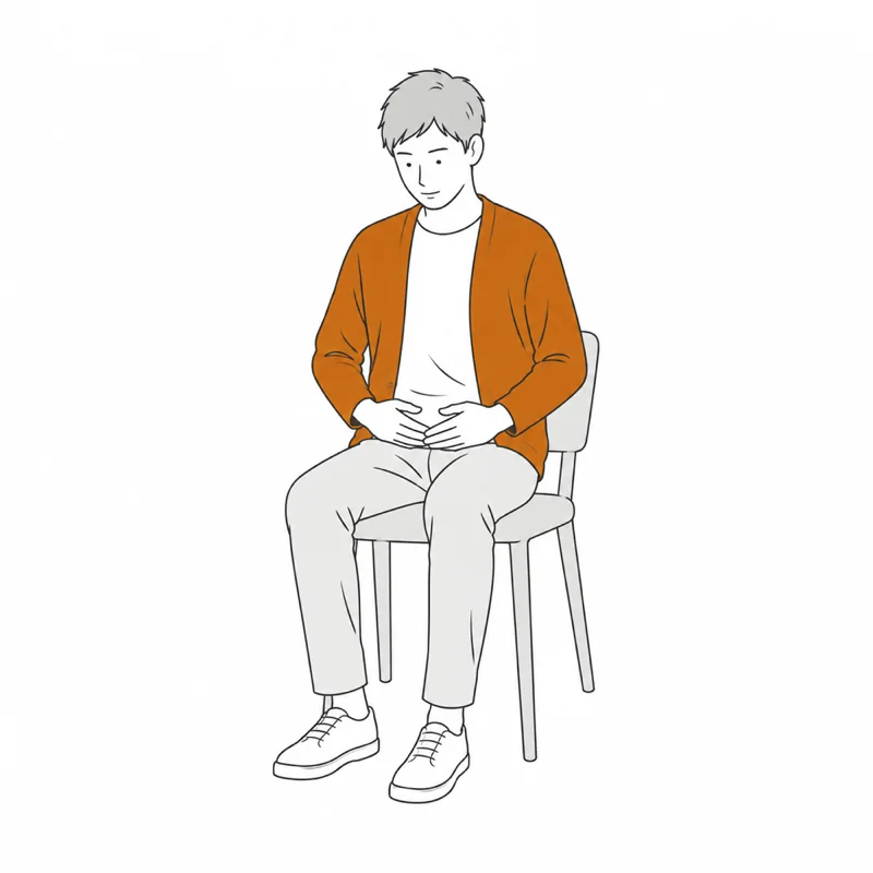椅子に座り、下腹部に両手を当てて静かにうつむく男性のイラスト