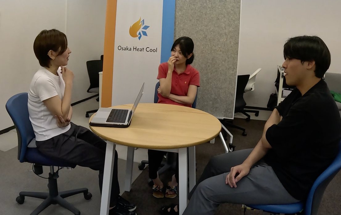円卓を囲んで、3 人が SenseChair に座って会話している様子。